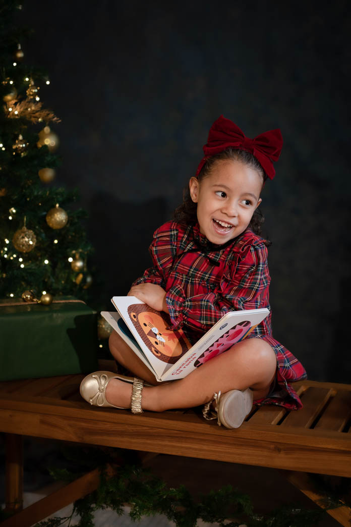 Niña sentada leyendo un cuento con sesiones de navidad de aleiram fotografia